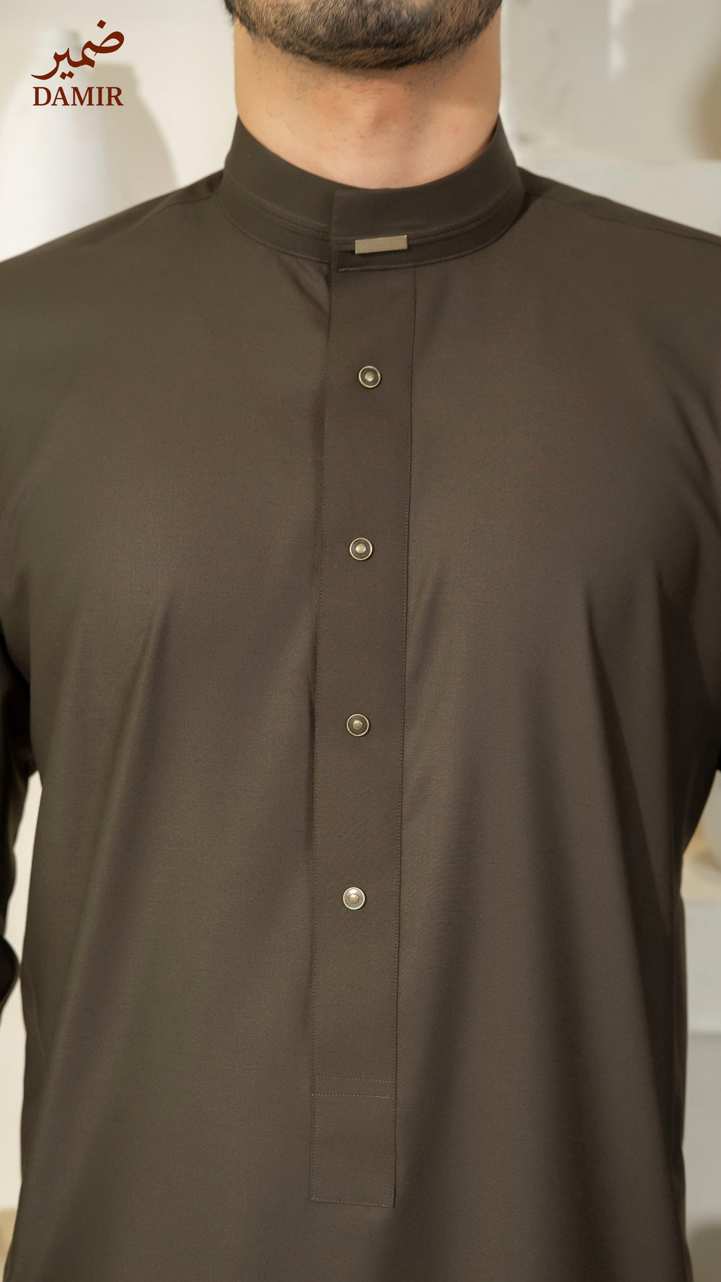 Dark brown traditional shirt worn by a person, with 'DAMIR' branding visible.