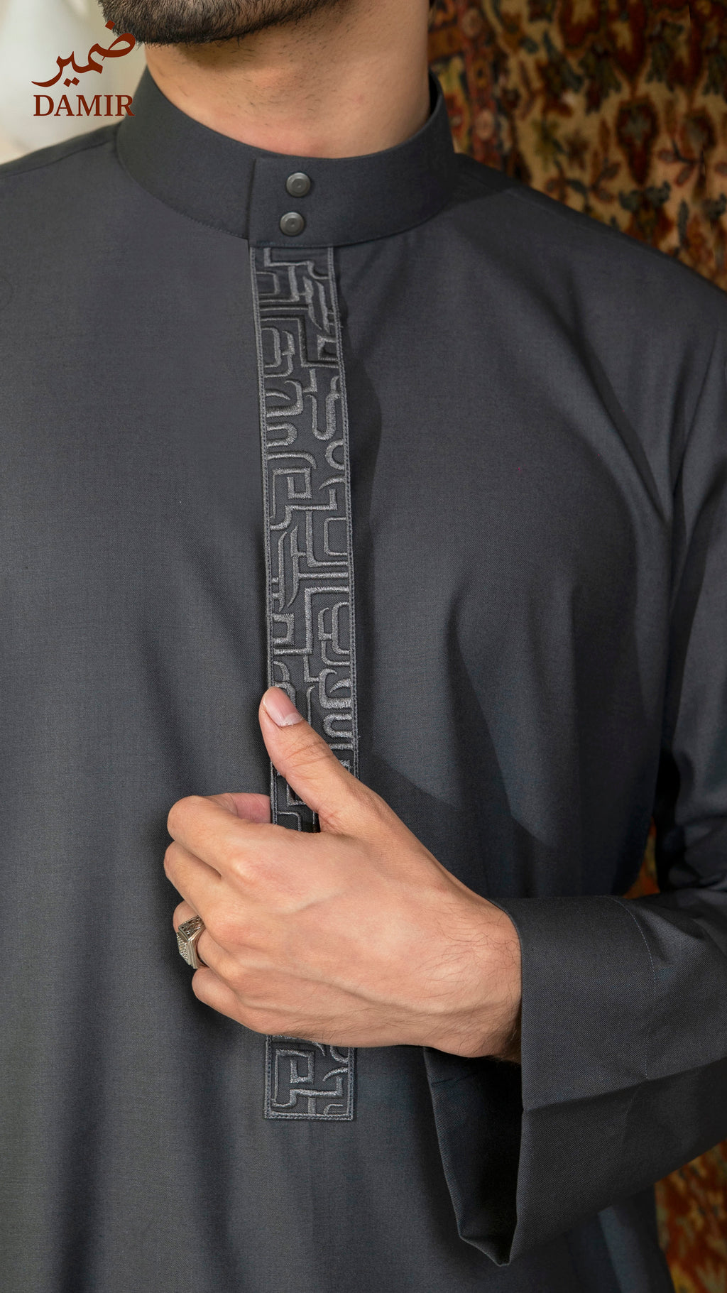 Person wearing a gray traditional outfit with intricate calligraphy design details.